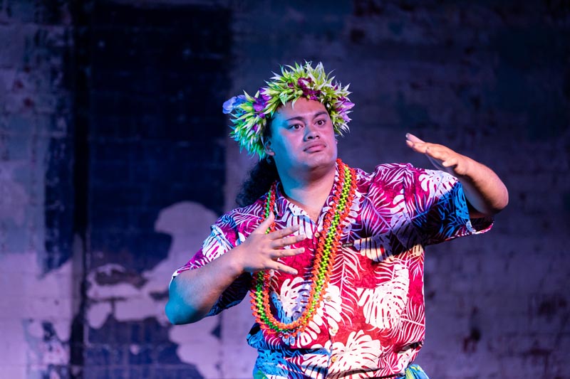 Jokani Coe performs wearing a colourful shirt, with lei around his head and neck 